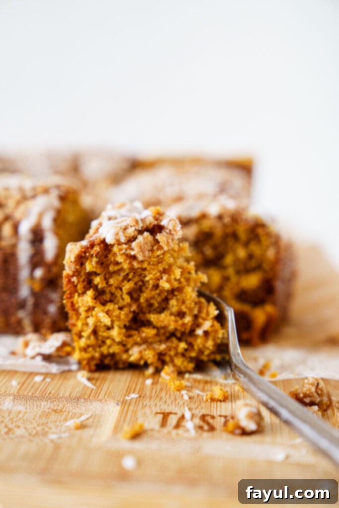A top-down view of a glazed pumpkin coffee cake in a pan with a decorative autumn leaf.