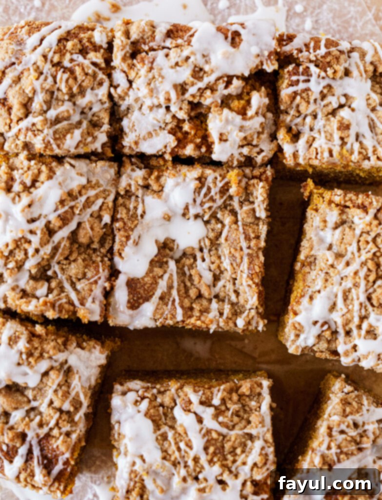 Two slices of glazed pumpkin coffee cake on a white plate with a fork.