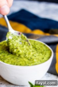 This Easy Chimichurri Sauce recipe is the best for grilled meats, veggies, as a marinade, or a dip! This traditional Argentinian sauce is ready in only five minutes and made with cilantro, parsley, olive oil, spice, and garlic. Also this sauce is naturally healthy, vegan, gluten free, low-card, whole 30, keto, and paleo. #sauce #chimichurri #easyrecipe #vegan Silver spoon dipping into white bowl of chimichurri sauce.