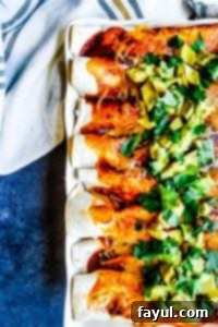 Overhead shot of enchiladas in a white baking dish with a white towel out of frame.