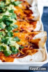 Shot of vegetarian enchilada in a white baking dish on a blue counter. 