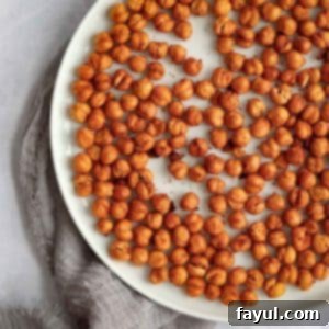 Overhead shot of crispy chickpeas on a white plate on a grey cloth.