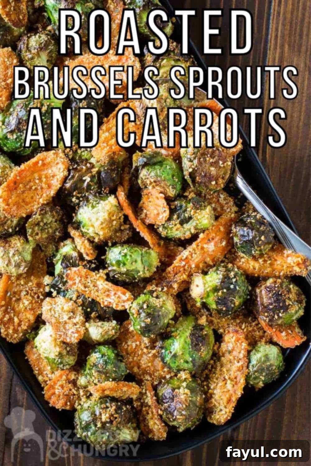 Overhead shot of roasted Brussel sprouts and carrots on a black plate on a dark wooden surface.