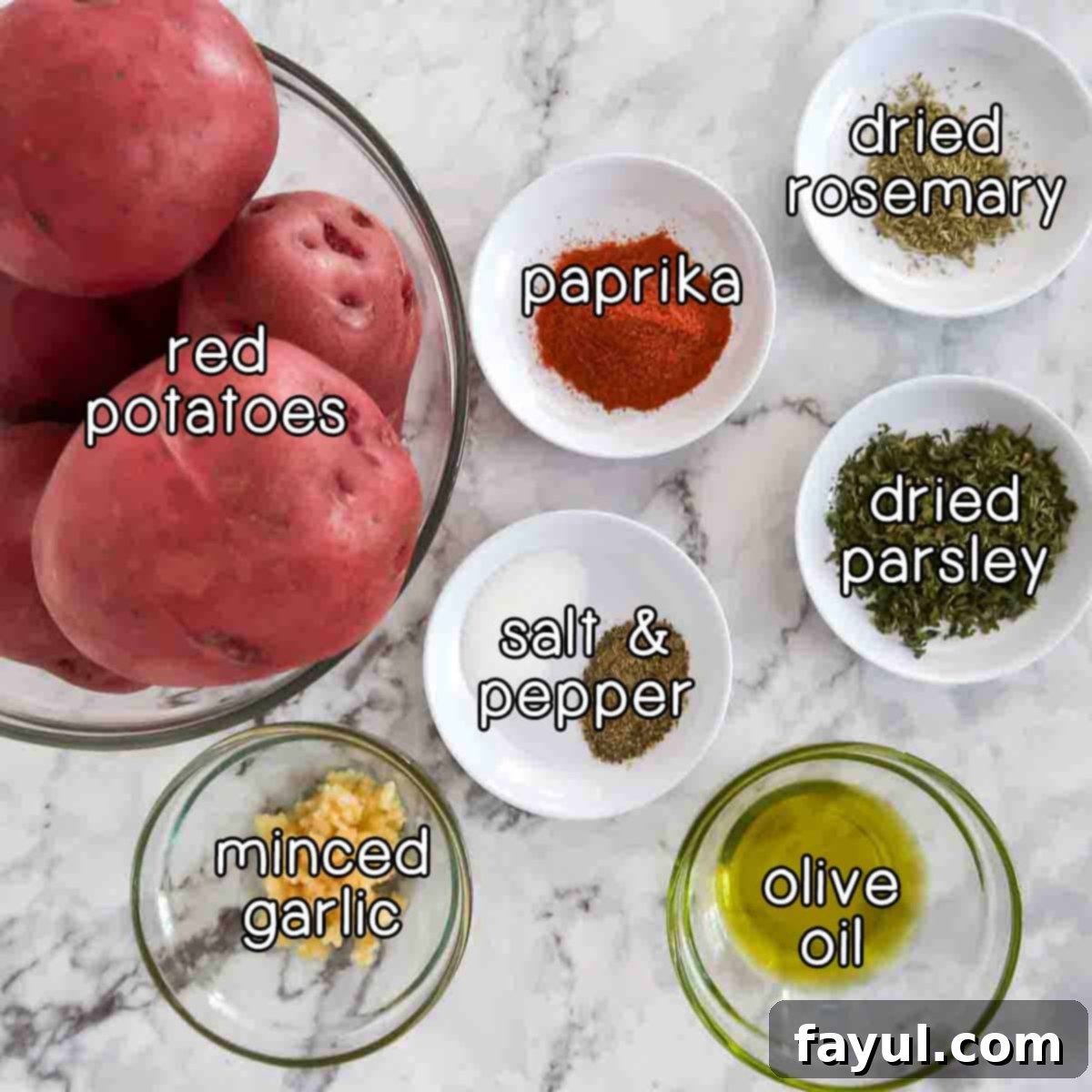 Overhead shot of all the simple ingredients required for making air fryer breakfast potatoes, including red potatoes, paprika, dried rosemary, dried parsley, salt, pepper, olive oil, and minced garlic, arranged on a blue surface.