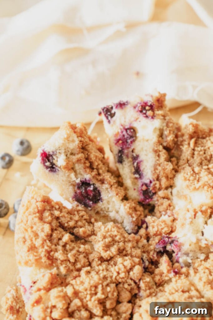 A slice of Blueberry Buckle Cake on a plate with fresh blueberries