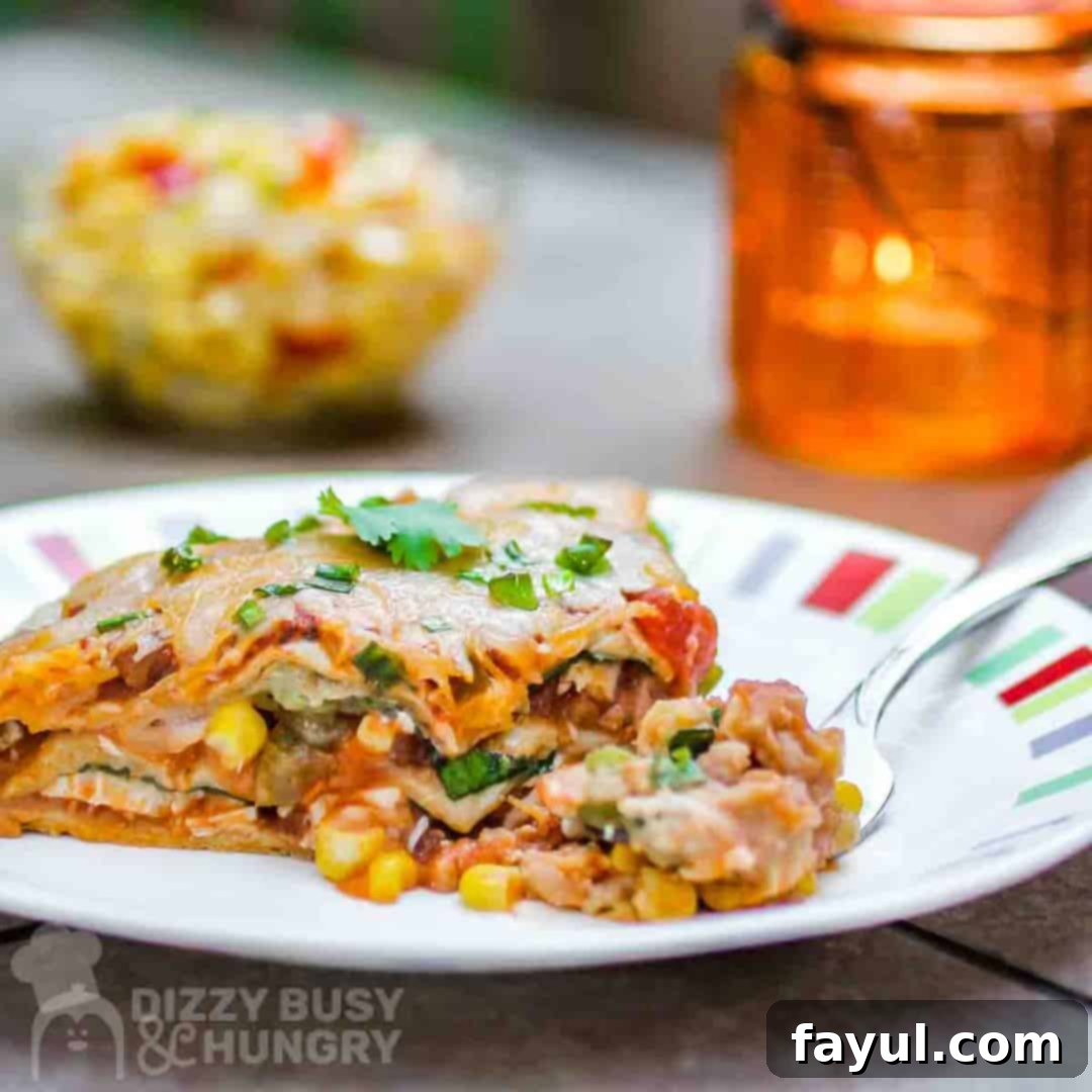 Close-up side view of a slice of vegetarian Mexican lasagna casserole, garnished with green onions, served on a colorful plate, showcasing its layers and melted cheese.
