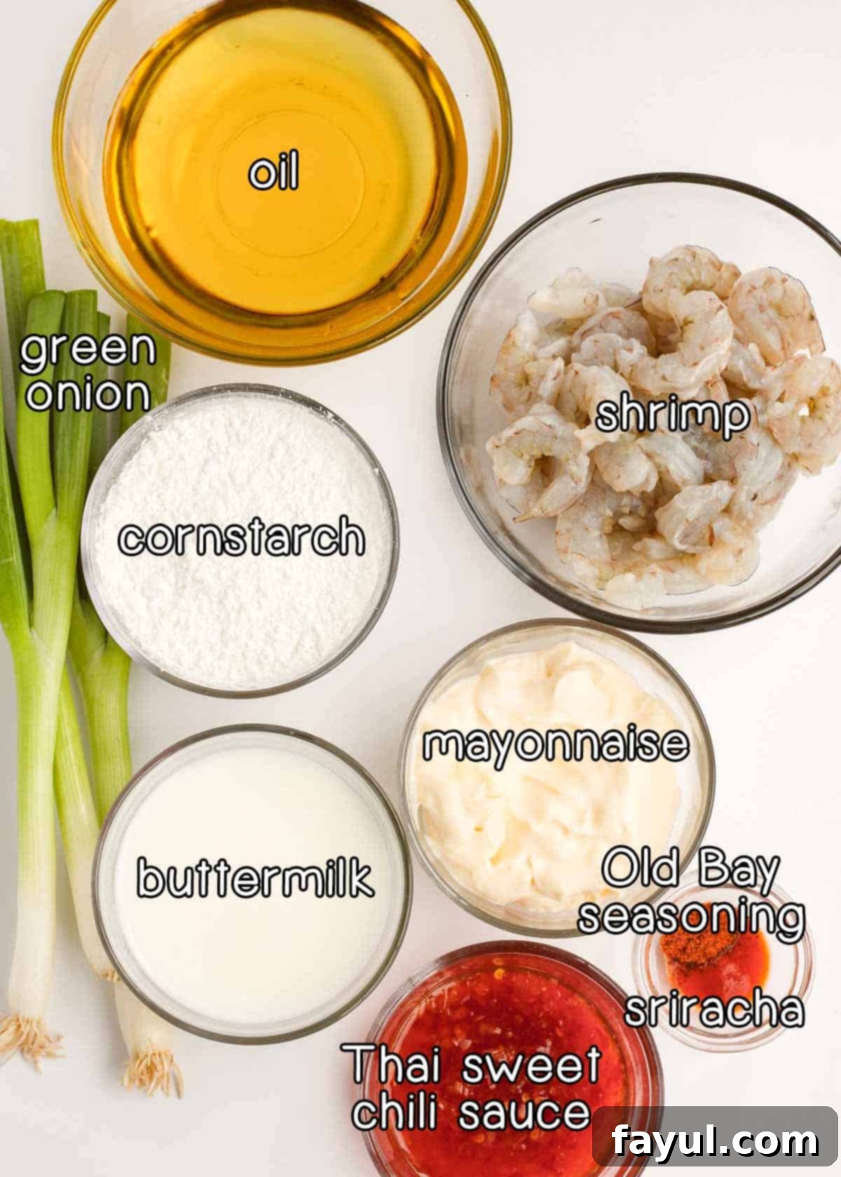 Overhead shot of ingredients - oil, green onion, cornstarch, shrimp, mayonnaise, buttermilk, Thai sweet chili sauce, old bay seasoning, and sriracha.