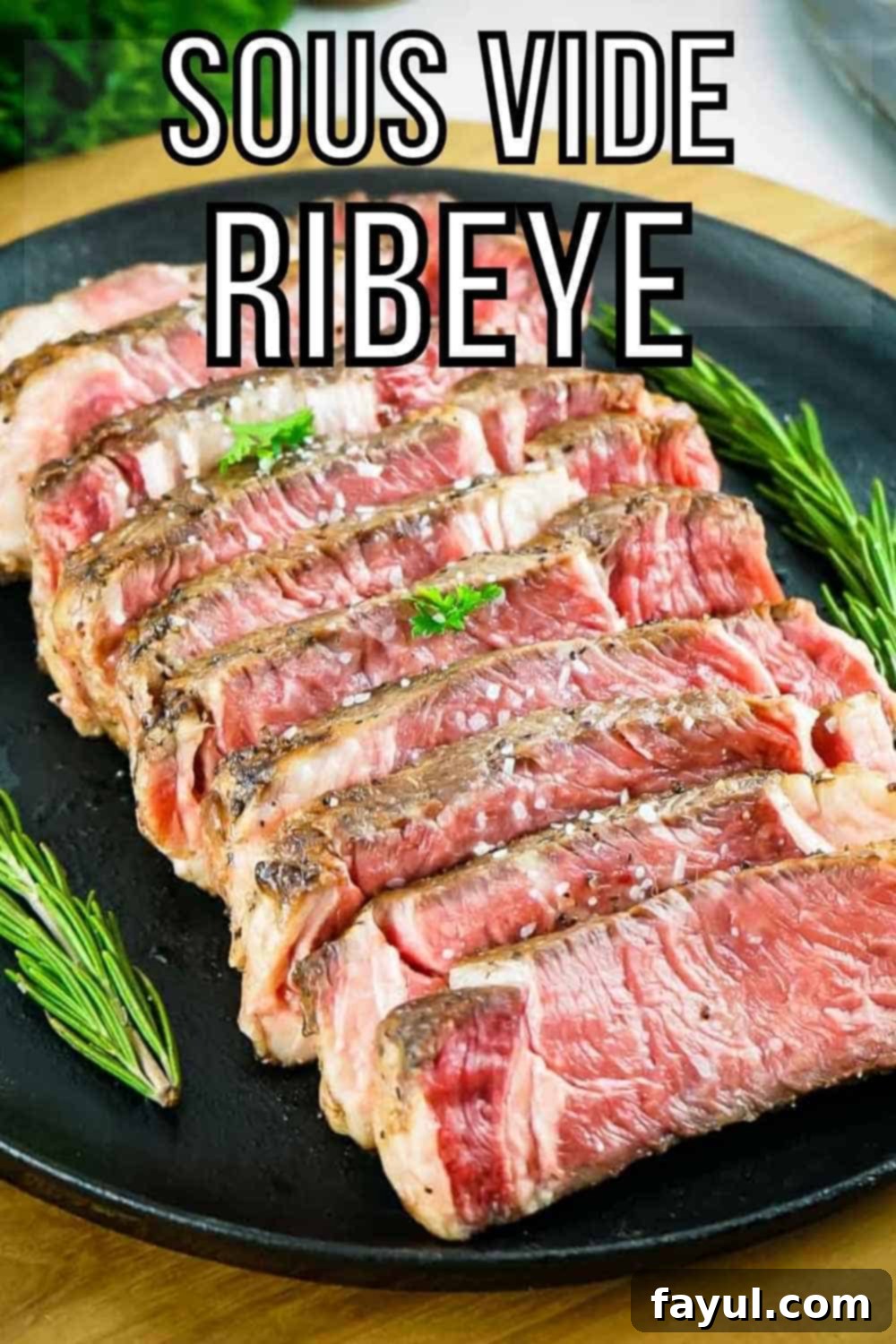 Side angled shot of multiple slices of rare ribeye garnished with salt and rosemary in a row on a black plate on a wooden surface.