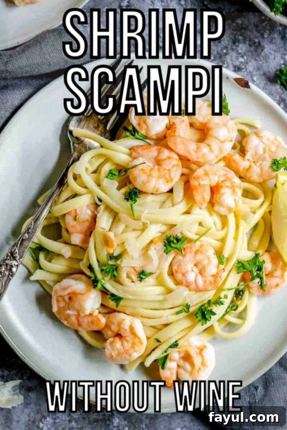 Overhead shot of shrimp scampi garnished with fresh parsley on a gray plate with a fork on a black and grey surface. The dish looks inviting and perfectly cooked.