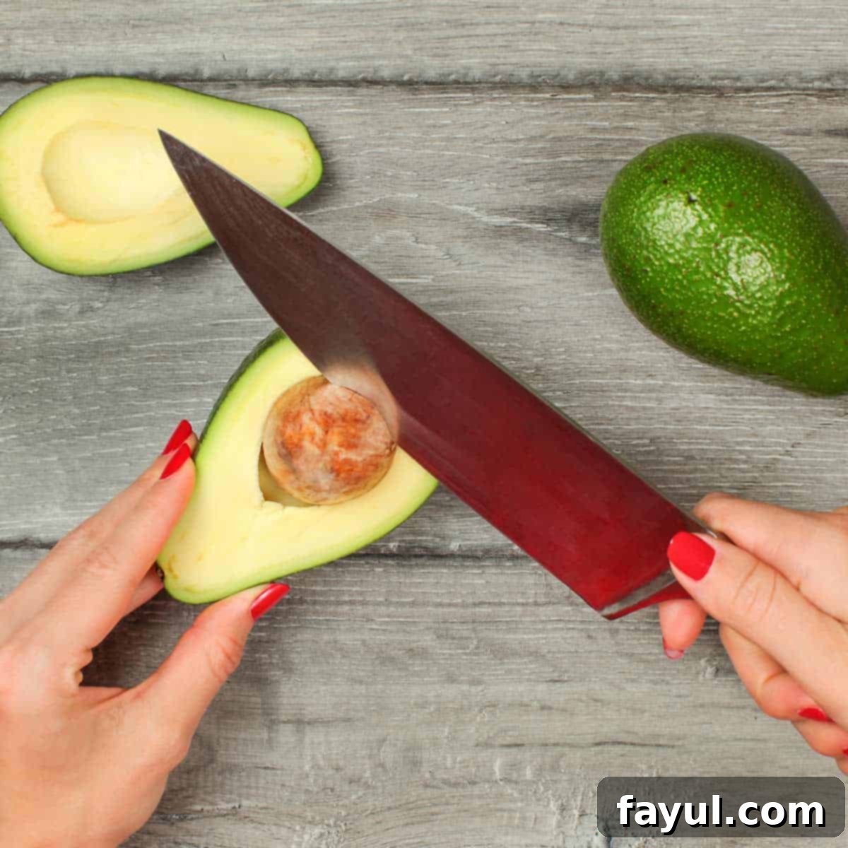 Avocado Flavor Demystified 6 Two hands with an avocado in the left hand and a knife in the right hand demonstrating how to remove the pit from an avocado.