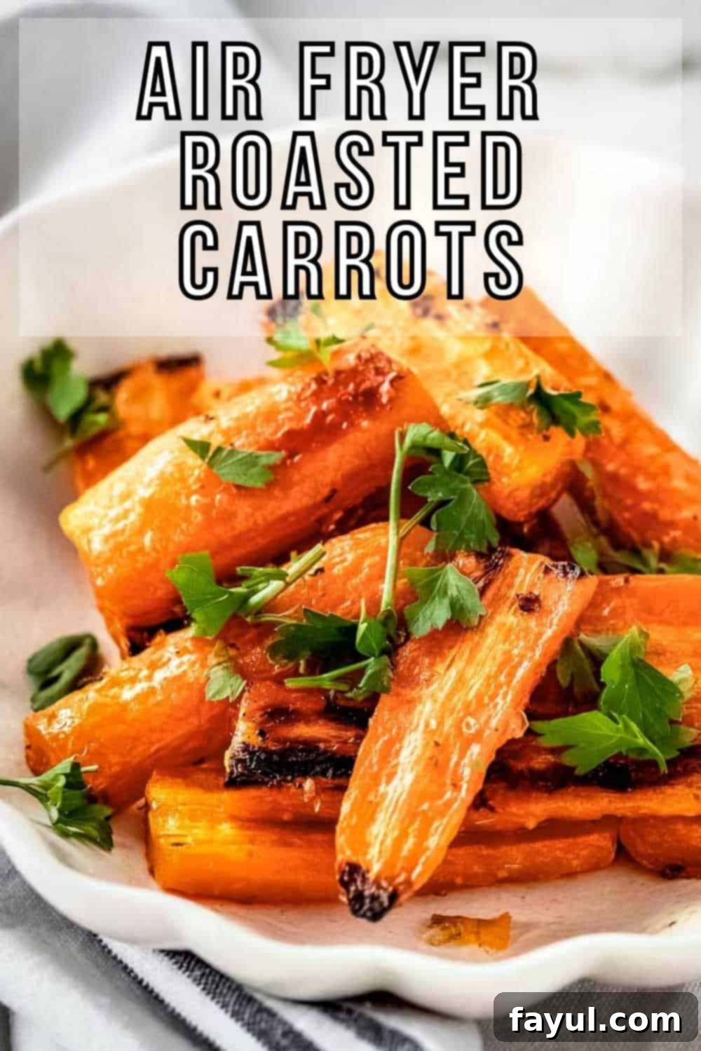 Side close up shot of roasted carrots garnished with herbs on a white plate on a grey cloth.