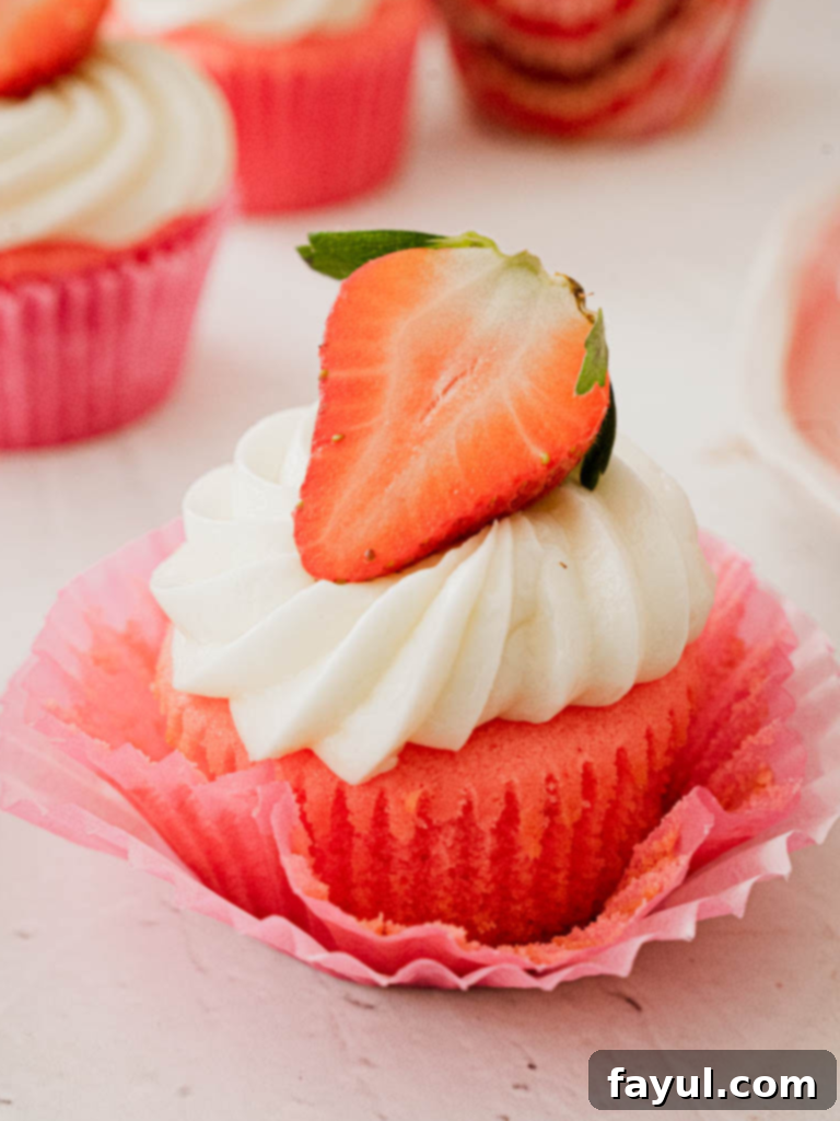 Delicious Strawberry Marshmallow Cupcake, topped with pink frosting and a fresh strawberry