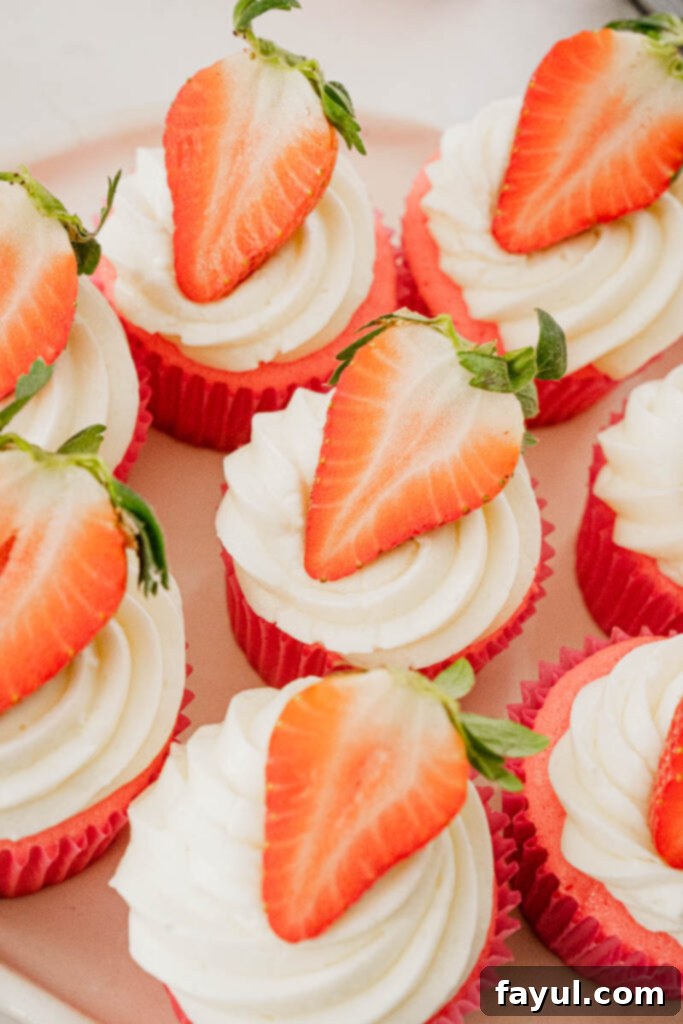 Two delightful strawberry marshmallow cupcakes, showcasing the fluffy frosting and strawberry garnish.