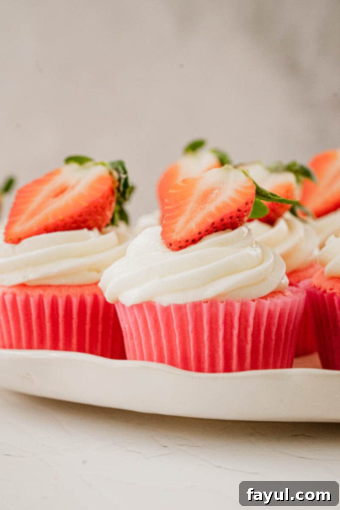 Two perfectly frosted strawberry marshmallow cupcakes on a white background, ready to be served.