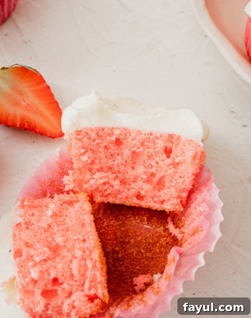 Rows of baked strawberry cupcakes cooling in their liners, ready for frosting.
