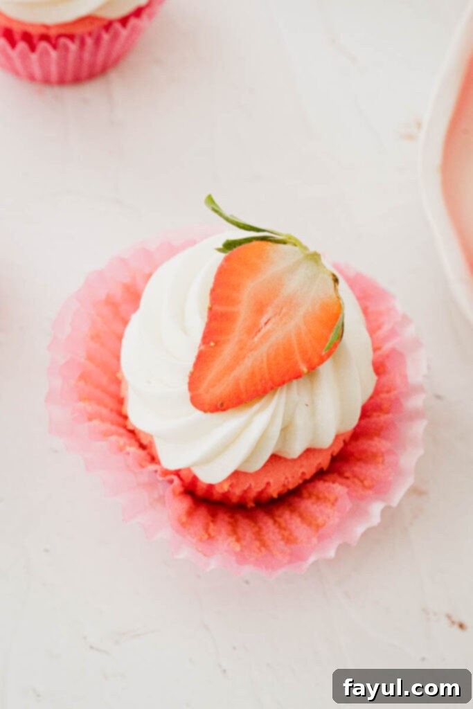 A freshly frosted strawberry marshmallow cupcake with a delicate swirl of pink and white buttercream.