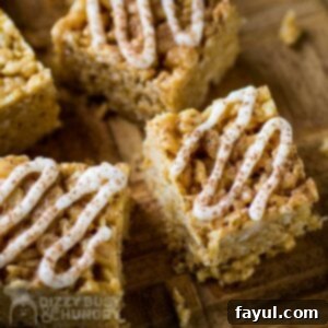 Close up shot of Peanut Butter Rice Krispie treats with icing drizzle on a wooden cutting board.