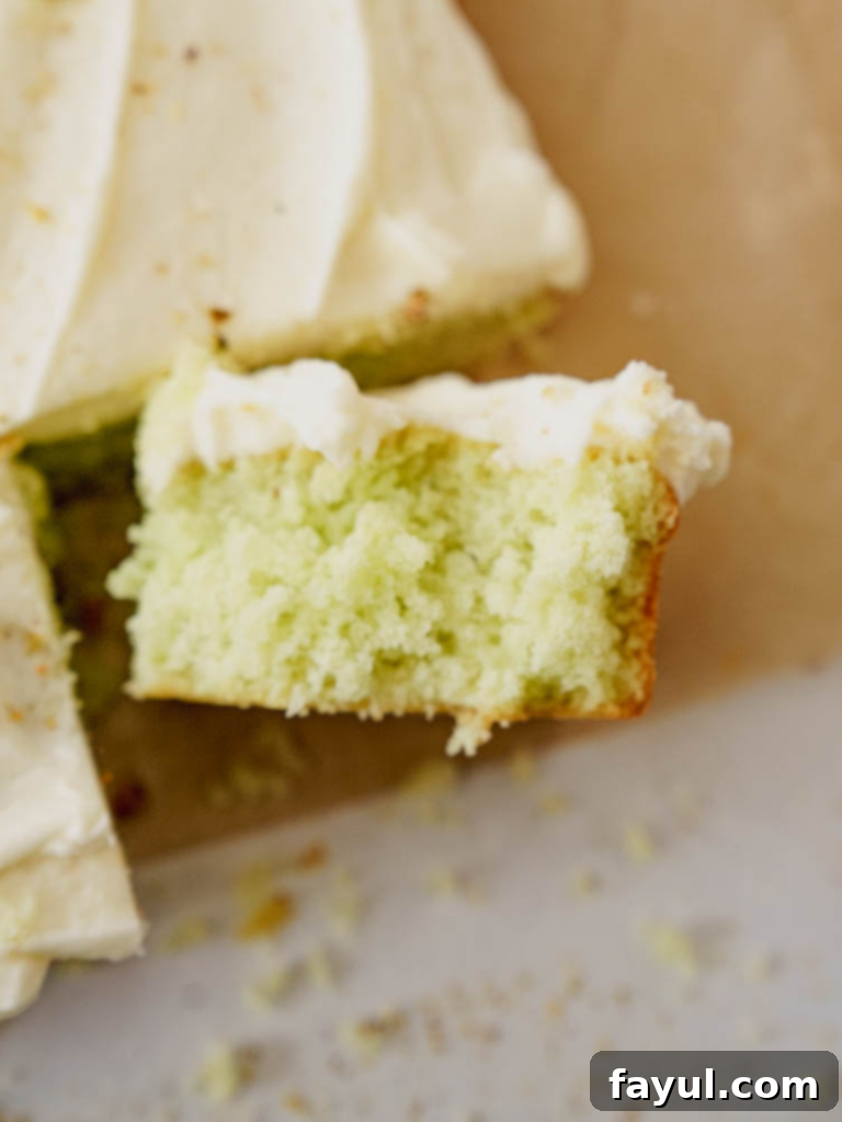 Slice of Pistachio Sheet Cake with cream cheese frosting and a sprinkle of pistachios