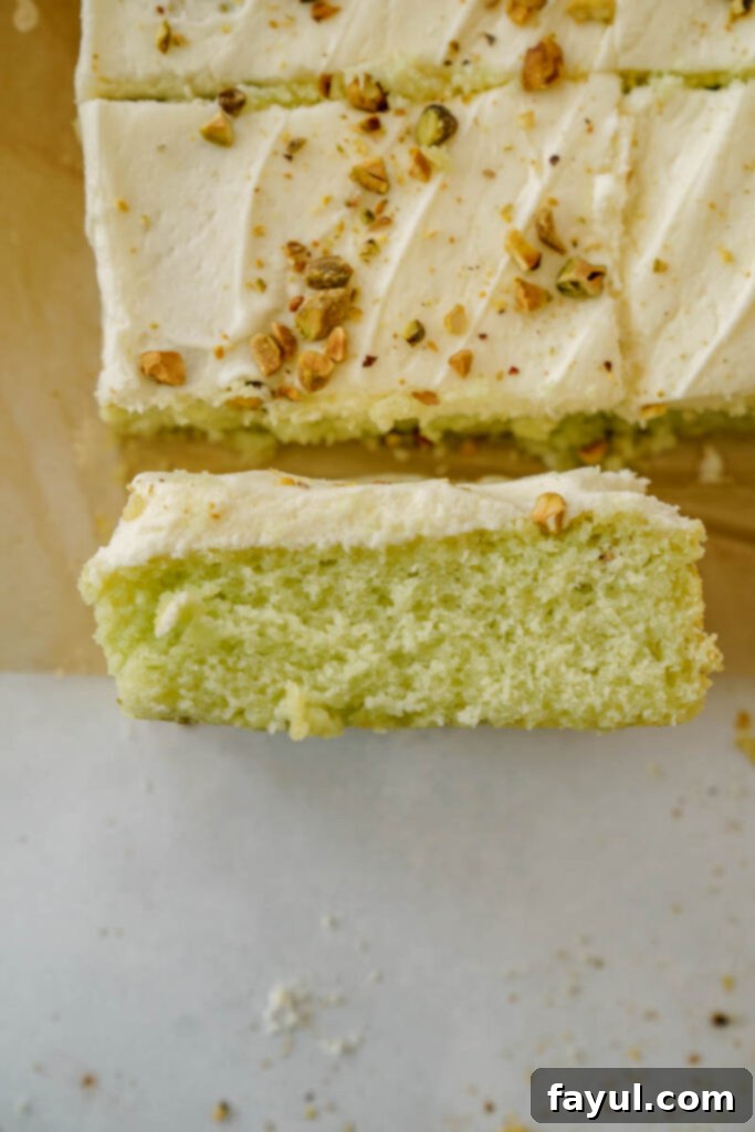 Pistachio Sheet Cake with a spatula spreading frosting