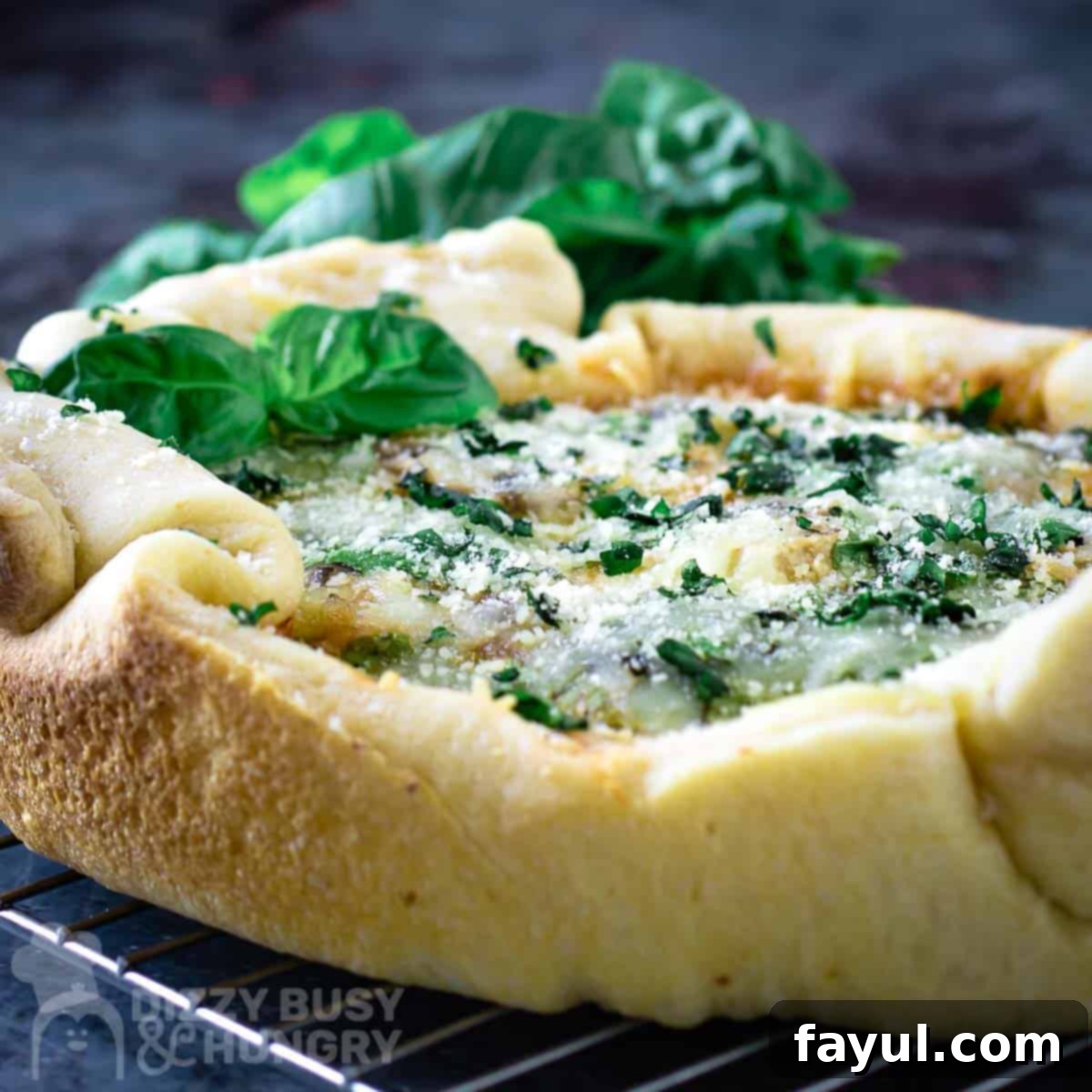 Side close up shot of crock pot pizza garnished with basil on a wire cooling rack.