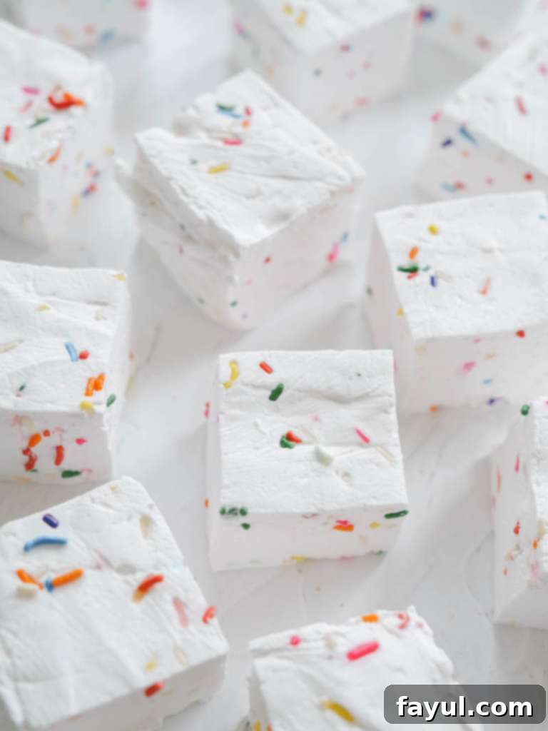 Homemade Birthday Sprinkle Marshmallows on a pink background, showcasing their soft, fluffy texture and colorful sprinkles.