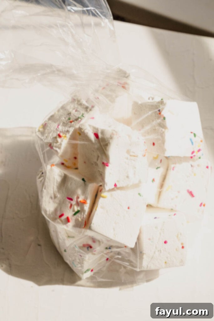 A close-up of a homemade funfetti marshmallow on a pink background, highlighting its colorful sprinkles.