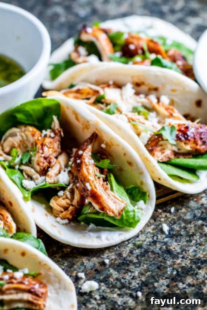 Tacos lined up on a stone counter.