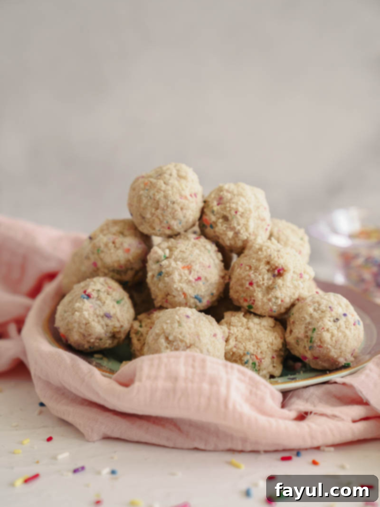 Vibrant Milk Bar style birthday cake truffles with colorful sprinkles and white chocolate coating on a white surface.