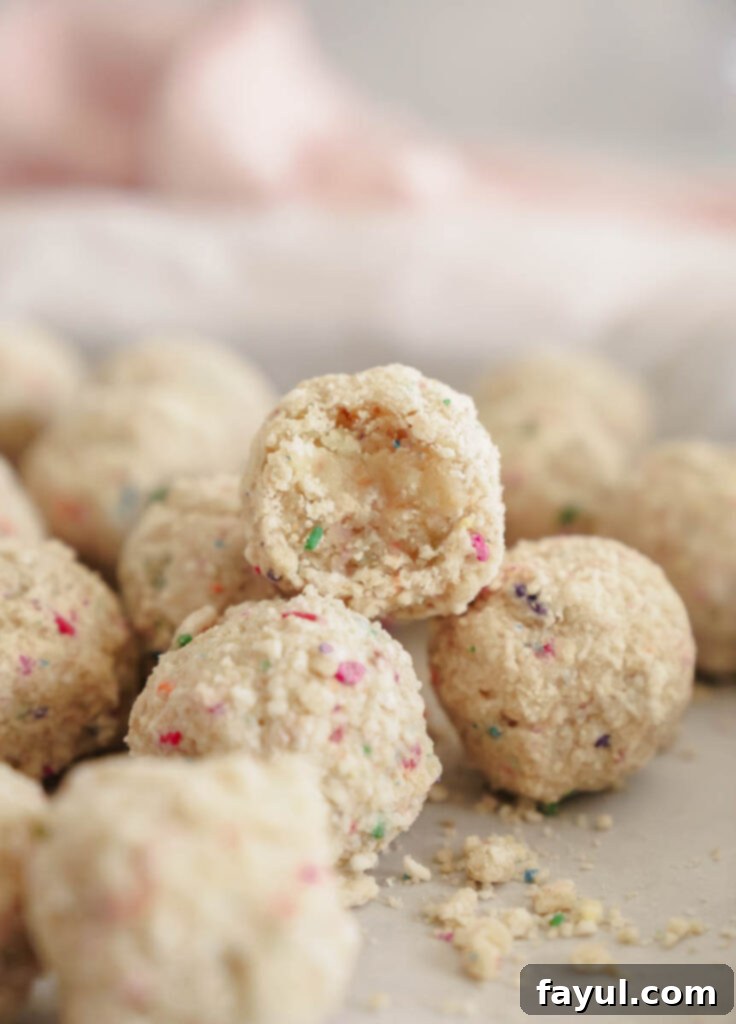Two Milk Bar style birthday truffles on a white plate with cake crumbs, captured from a high angle.