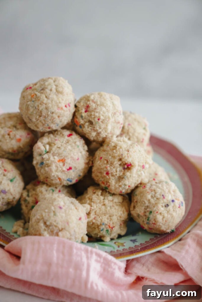 Close-up of a single Milk Bar style birthday truffle, showing the white chocolate coating and vibrant funfetti crumbs.