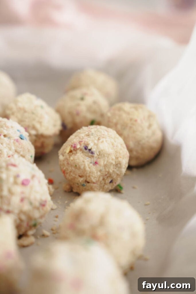 Freshly made Milk Bar style birthday truffles covered in crumbs, cooling on a wire rack.