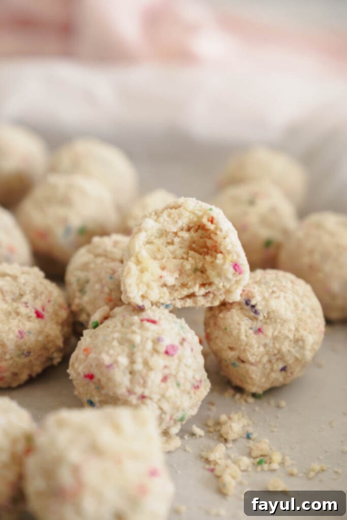 A beautifully arranged stack of Milk Bar style birthday truffles, glistening with white chocolate and colorful crumbs, in a festive setting.