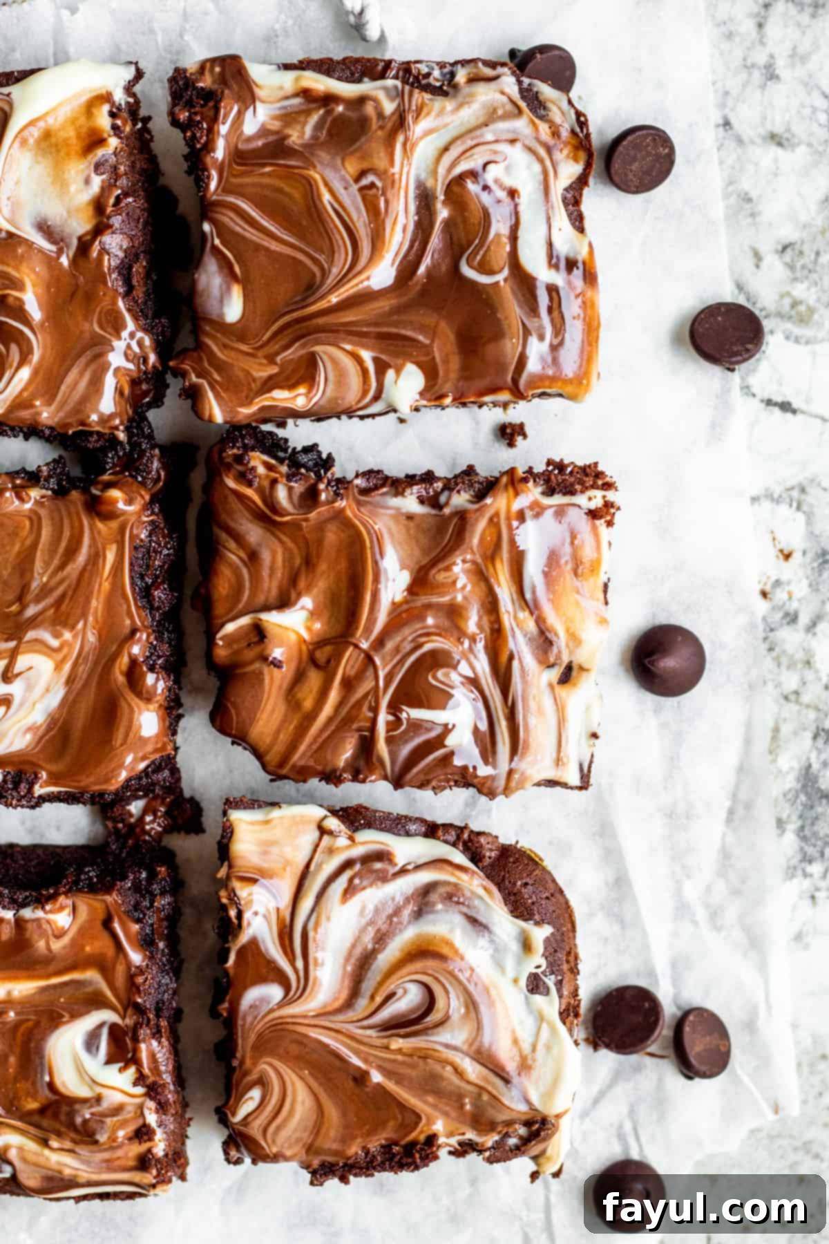 Overhead shot of brownies sliced on white parchment paper.
