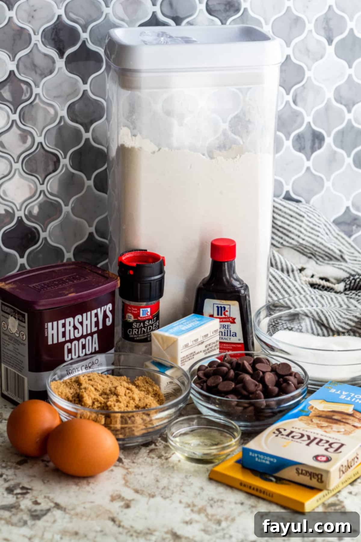 Brownie ingredients laid out on white counter in containers and small bowls.