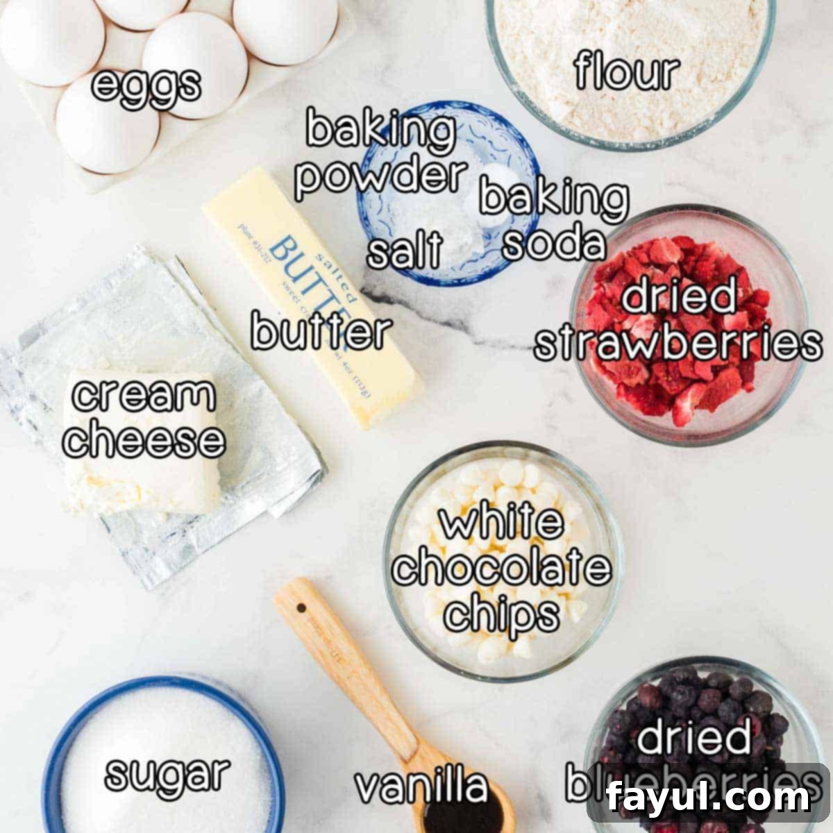 Overhead shot showcasing all the essential ingredients laid out on a clean surface for making red, white, and blue cookies: fresh eggs, all-purpose flour, baking powder, baking soda, salt, bright freeze-dried strawberries, softened butter, cream cheese, white chocolate chips, plump freeze-dried blueberries, rich vanilla extract, and granulated sugar.