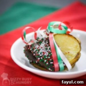 Side shot of multiple chocolate covered potato chips wrapped in red, green, and white ribbon on a small white plate on red and green tissue paper.