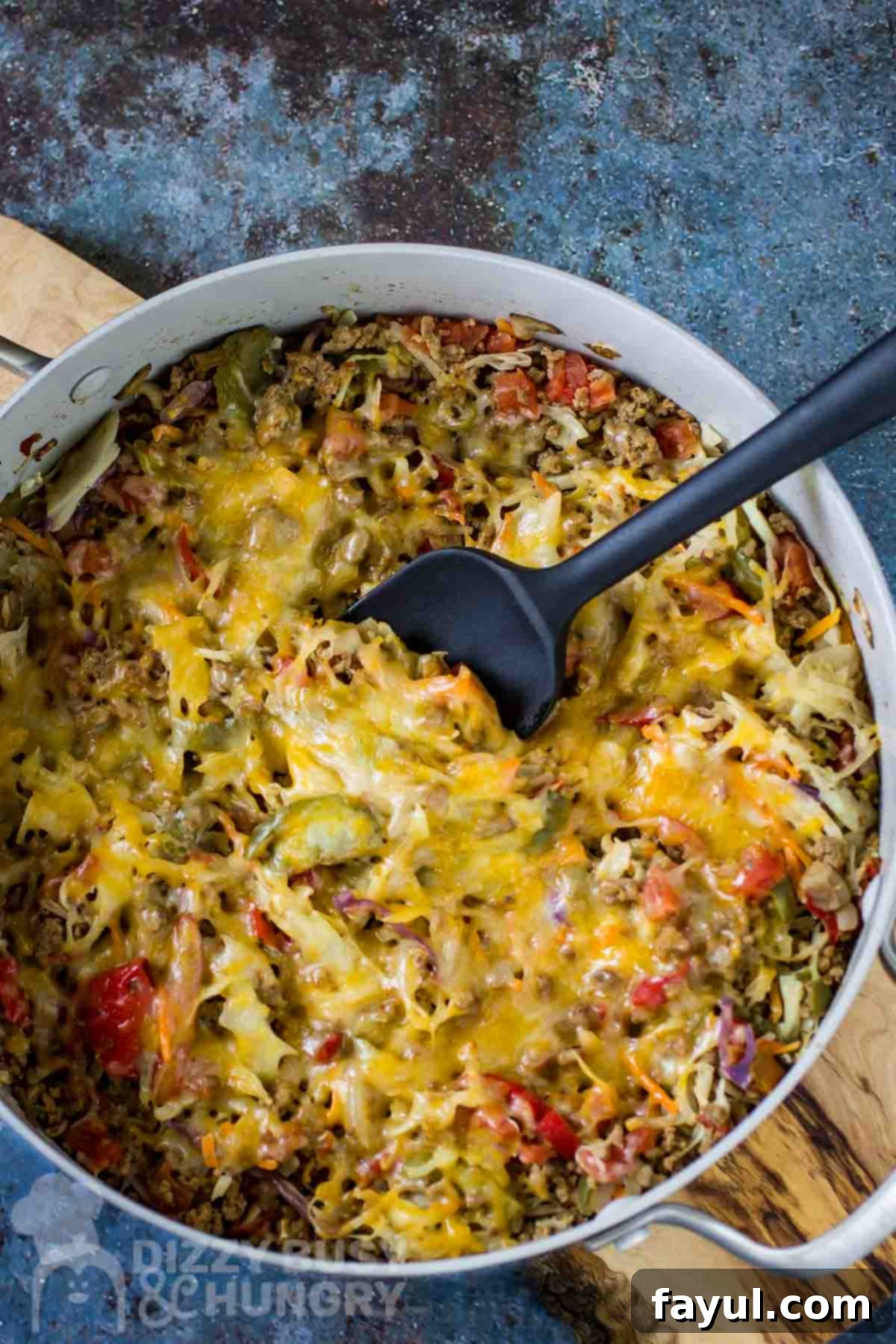 Overhead shot of a delicious One-Skillet Stuffed Cabbage Casserole in a large shallow pot with a black spatula, resting on a rustic wooden surface. Perfect for a quick low-carb weeknight meal.
