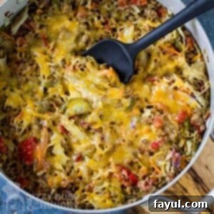 Overhead shot of delicious One-Skillet Stuffed Cabbage Casserole in a large shallow pot with a black spatula, resting on a rustic wooden surface. Perfect for a quick low-carb weeknight meal.