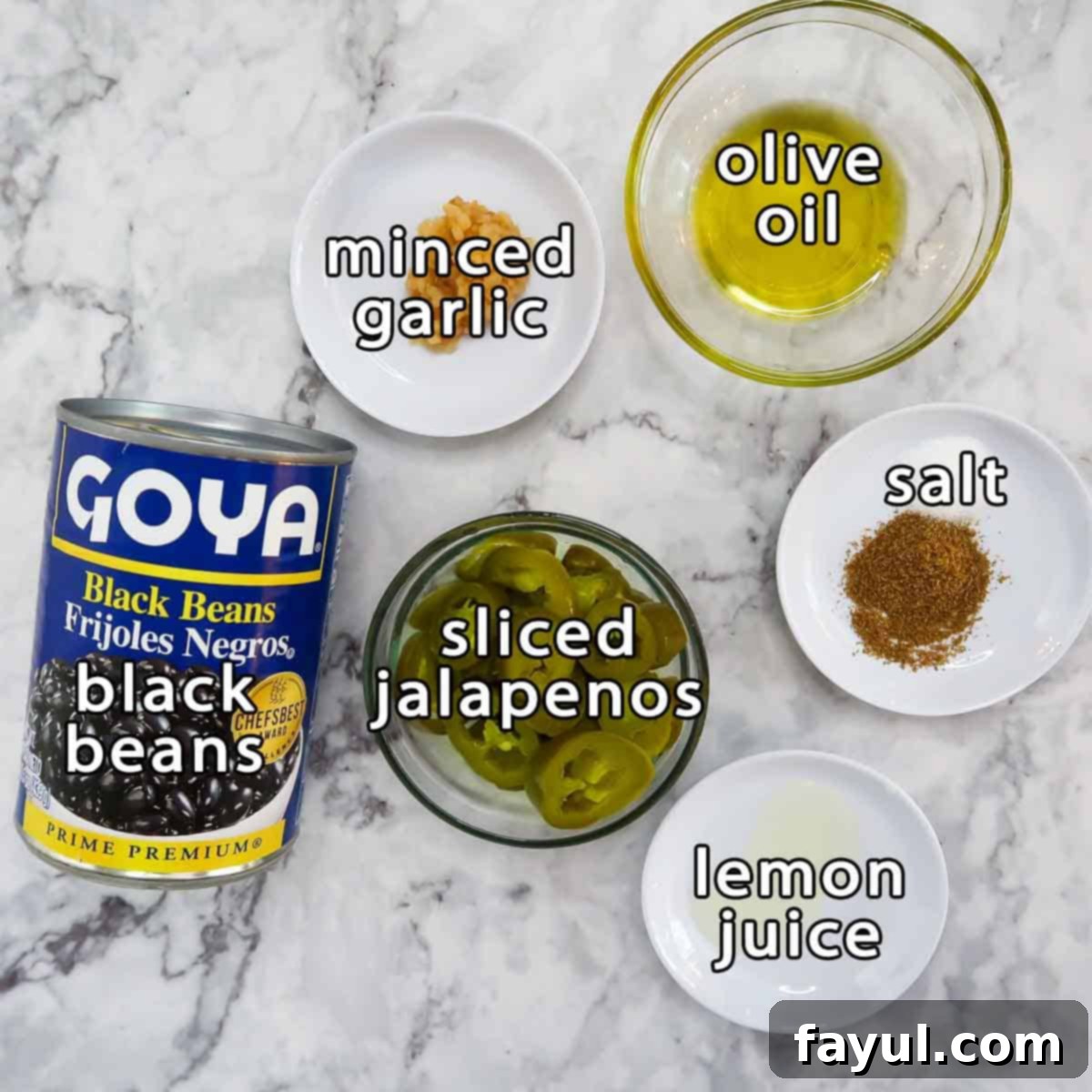 Overhead shot of ingredients - black beans, sliced jalapeños, lemon juice, salt, minced garlic, and olive oil.
