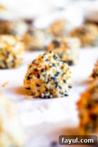 Close up of a single Everything Bagel Cheese Ball Bite on parchment paper on a cookie sheet, ready for chilling.