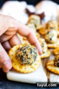 Hand picking up an Everything Bagel Cheese Ball Bite from a cutting board.