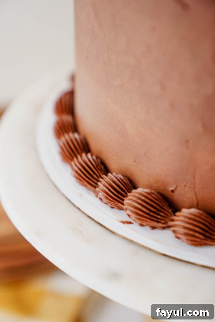 Hand placing a slice of yellow cake with chocolate frosting on a plate