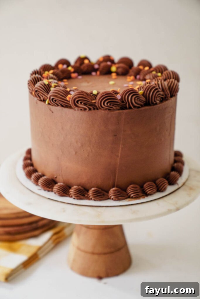 Hand holding a slice of yellow cake with chocolate frosting