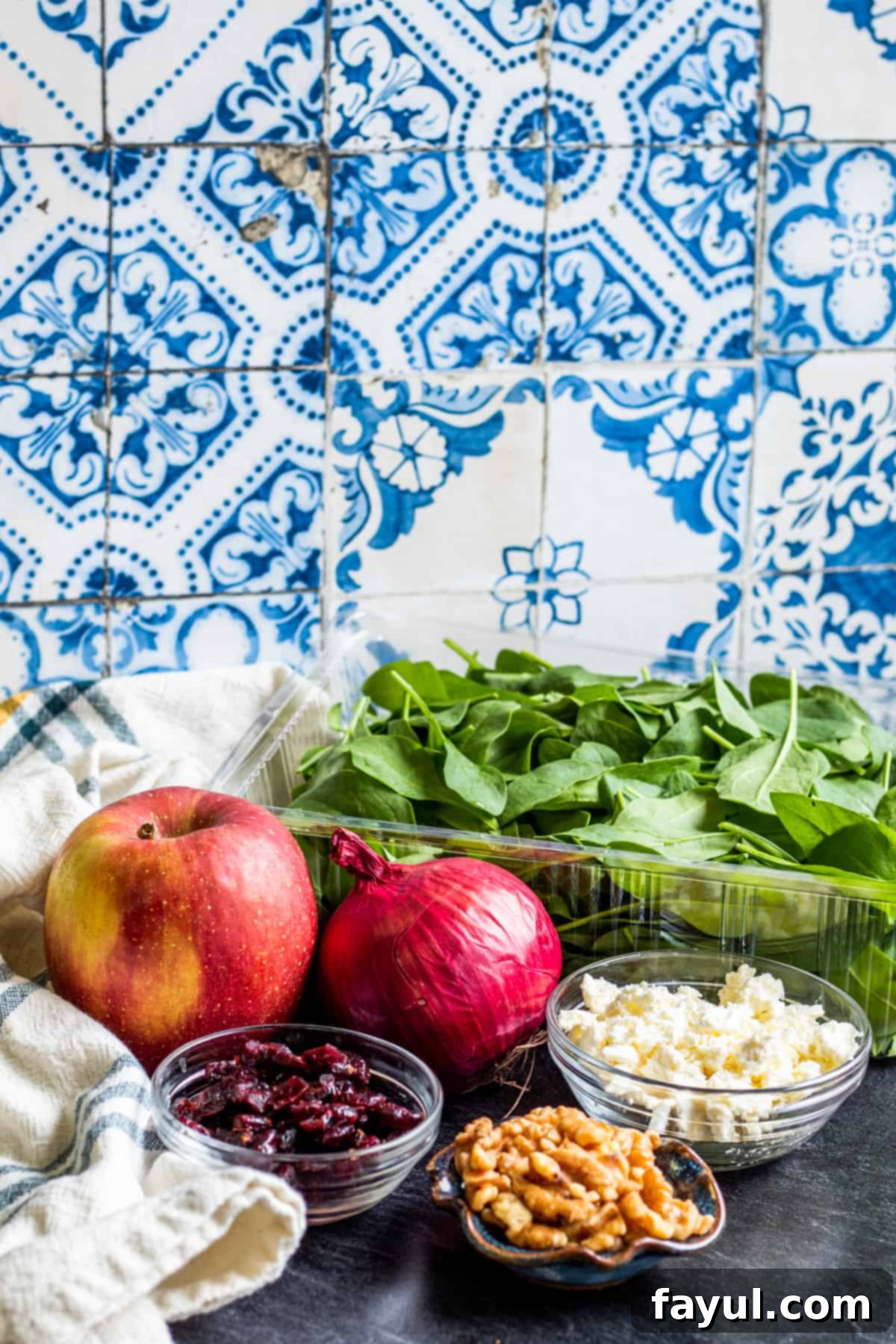 Orchard Greens with Honey Balsamic Drizzle 2 Spinach salad ingredients laid out on dark blue counter in bowls.
