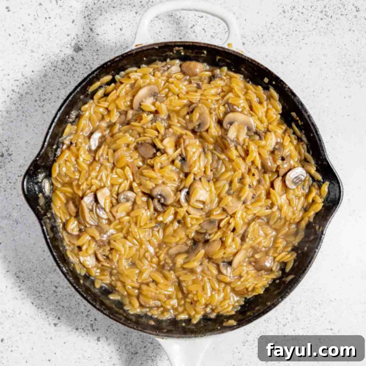 Overhead view of process shot 5 - bringing the orzo mixture to a boil, then lowering to a simmer, covering the skillet, and cooking for 8-10 minutes.
