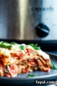 Straight-on shot of a slice of vegetarian lasagna on a gray plate, clearly showing the various layers.