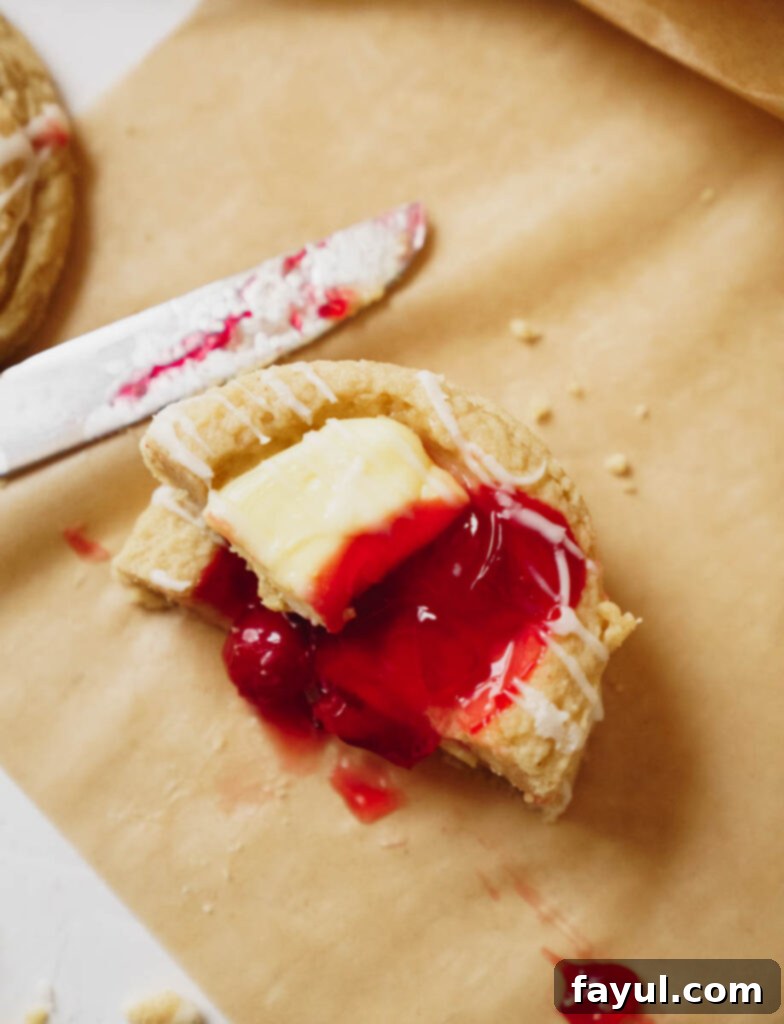 Two cherry cheesecake cookies on a white plate, close up