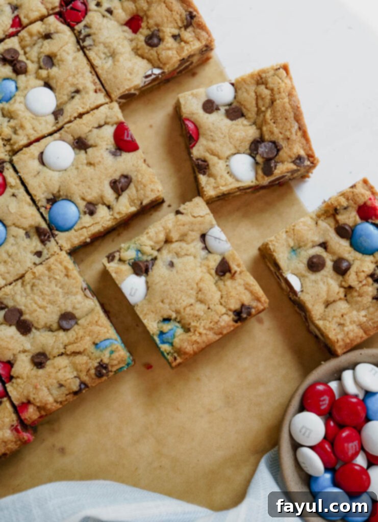 A slice of Firework Blondie with visible chocolate chips and colorful M&M's.