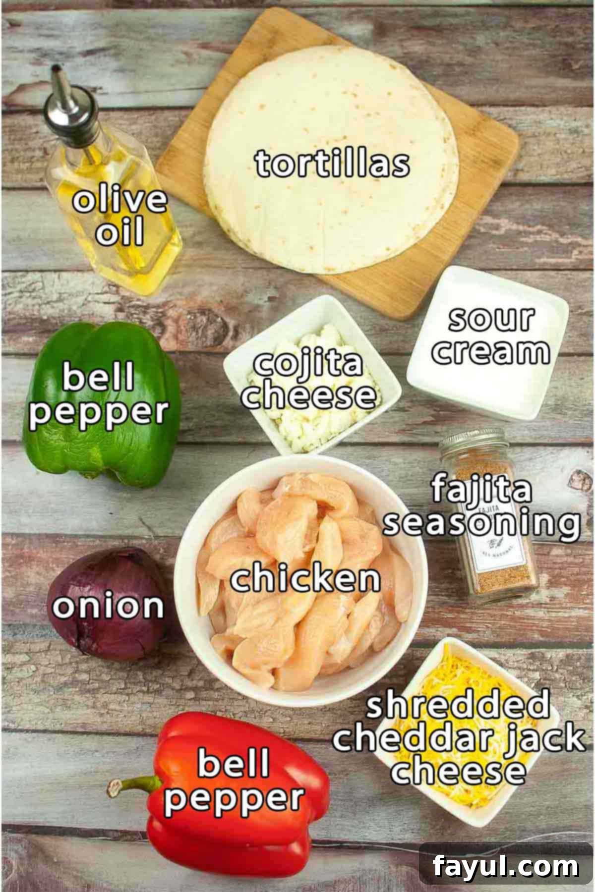 Overhead shot of ingredients - tortillas, olive oil, bell pepper, cotija cheese, sour cream, onion, chicken, bell pepper, shredded cheddar jack cheese, and fajita seasoning.