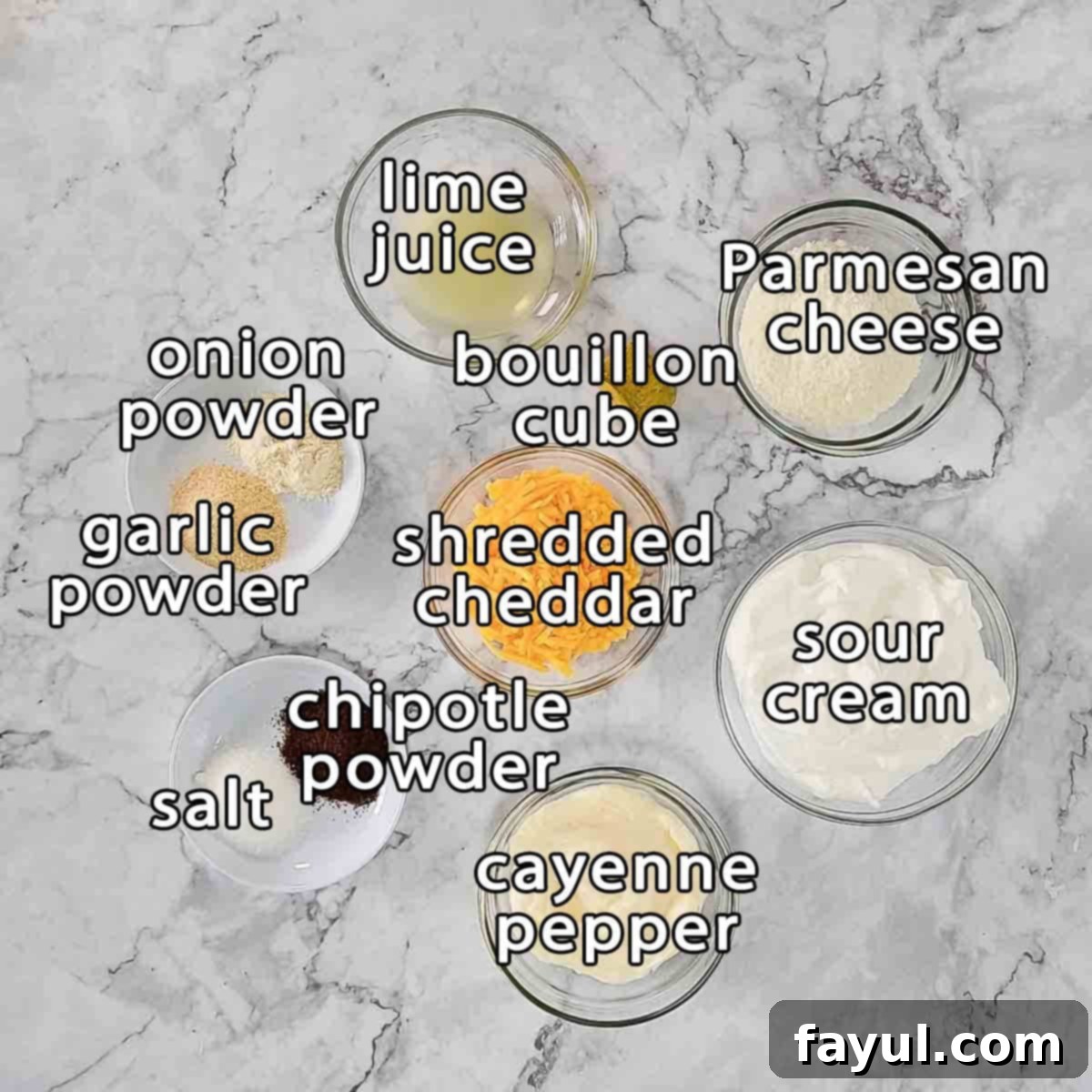 Overhead shot of ingredients - lime juice, parmesan cheese, bouillon cube, shredded cheddar, sour cream, cayenne pepper, chipotle powder, salt, garlic powder, and onion powder.